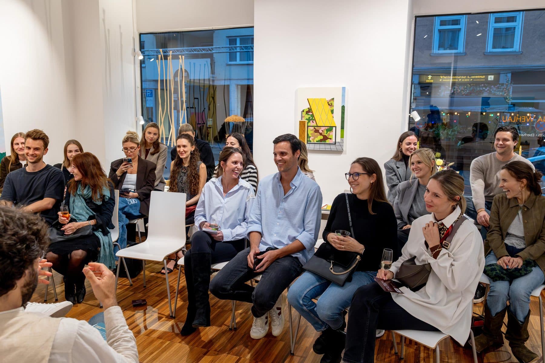 Das Publikum sitzt im Kreis zwischen den Bildern der Galerie
