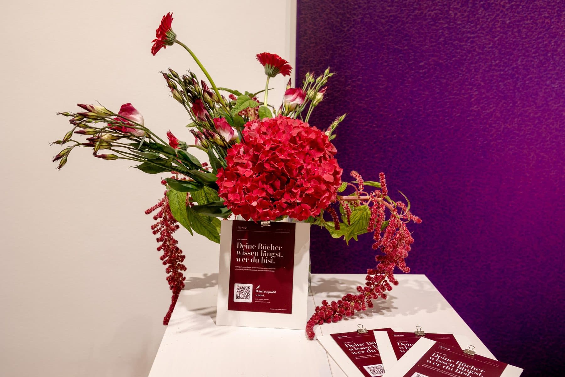 Blumenstrauß und das Buch des Abends vor einer violetten Wand